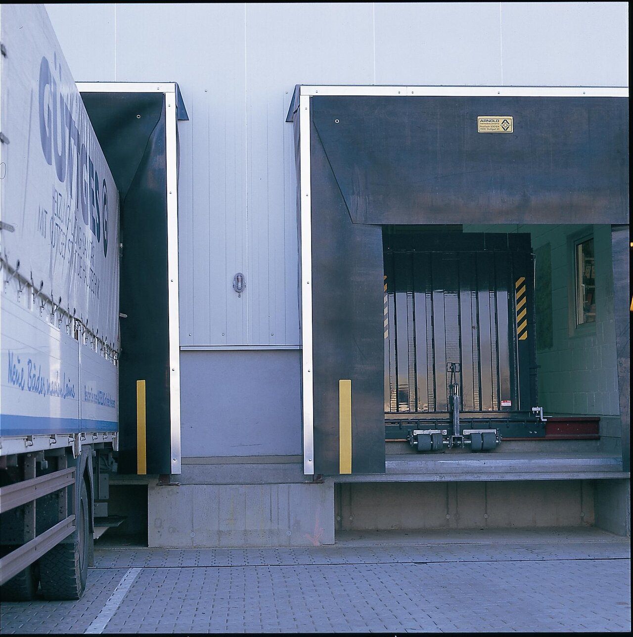 seitenverschiebbare Verladebrücke (Federbrücke) aus Stahl in vertikaler Ruheposition an der Rampe.